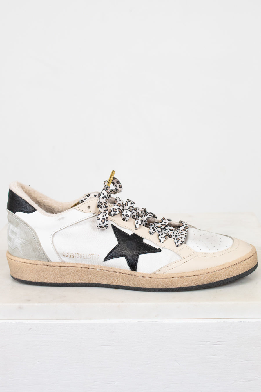 White sneaker with black star and embellishments on a white background