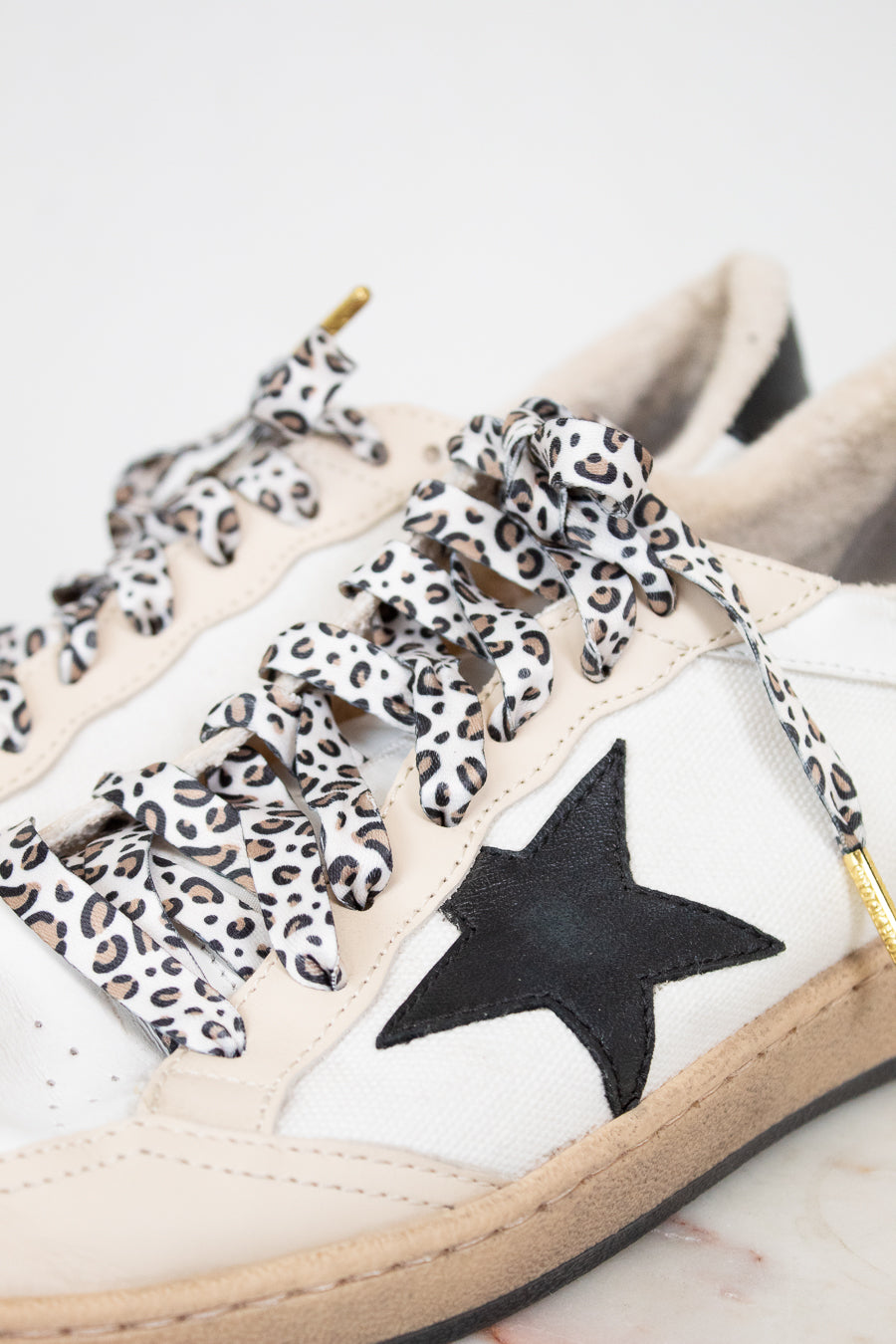 White sneakers with leopard print laces and a black star on a light background