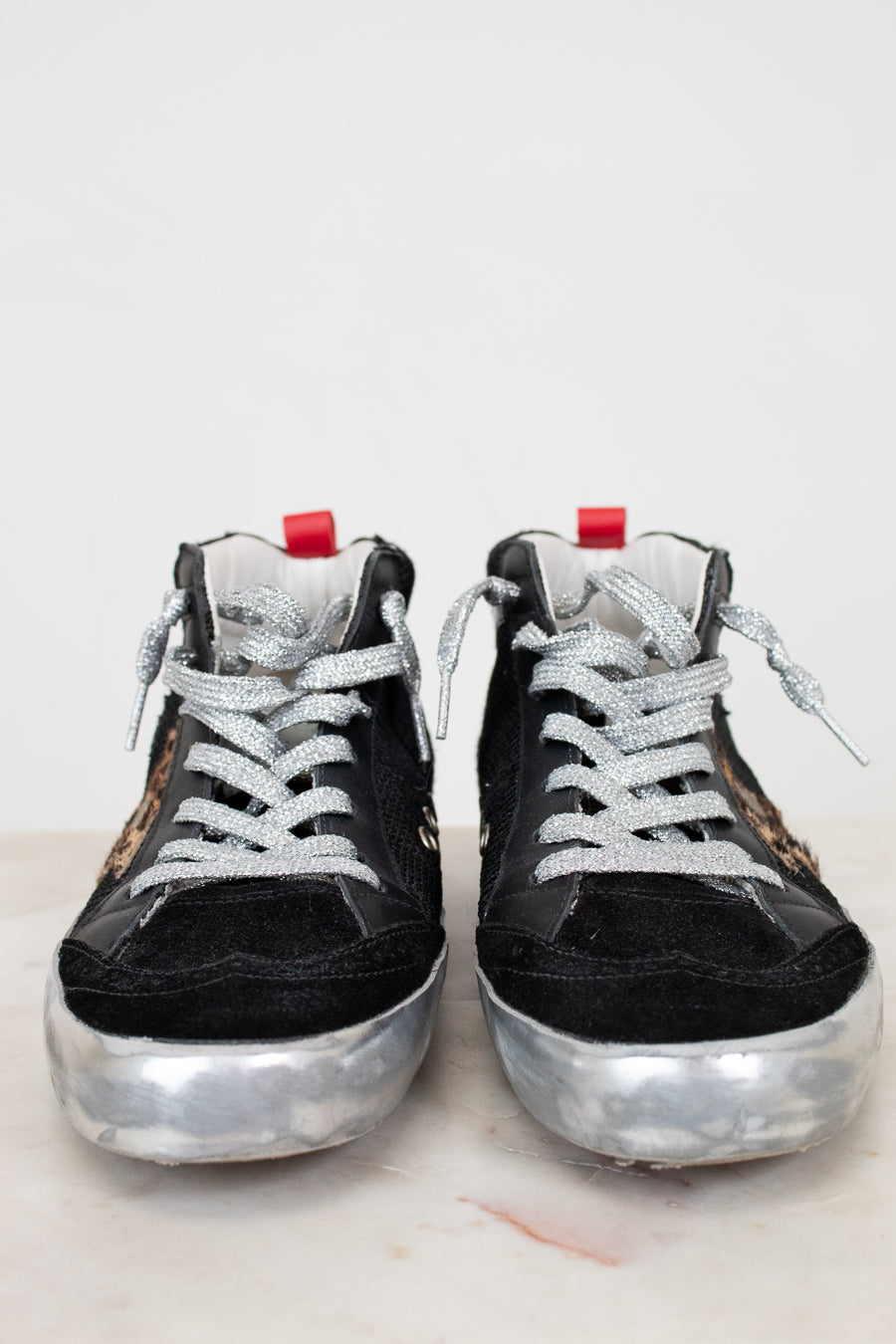 Black high-top sneakers with silver soles on a light background