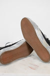 Close-up of black sneakers with brown soles on a light gray background