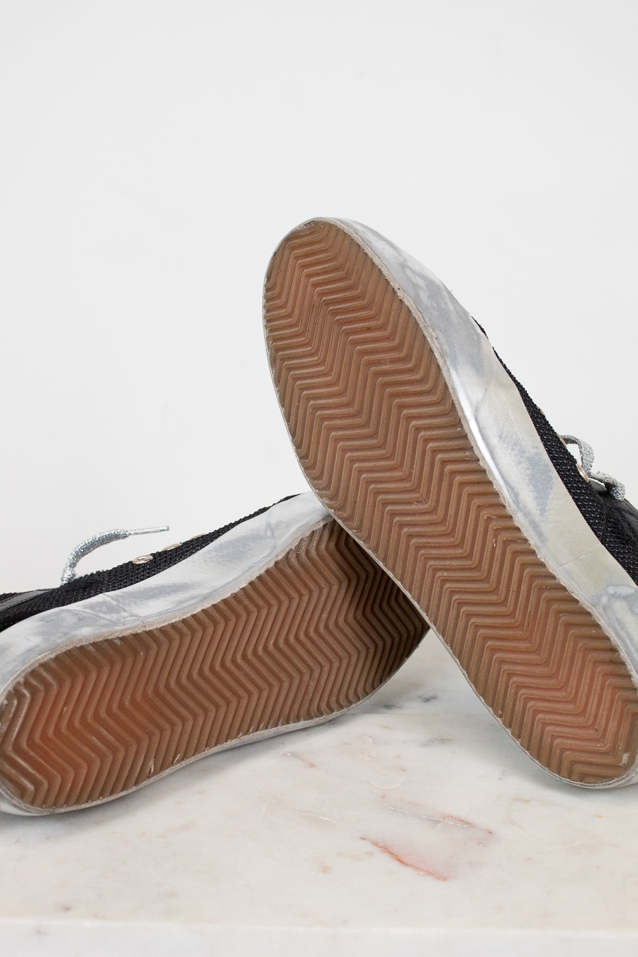 Close-up of black sneakers with brown soles on a light gray background
