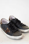 Black sneakers with gold star and dot patterns on a light background