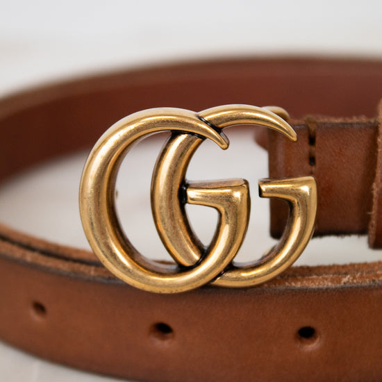 Brown leather belt with a gold Gucci buckle on a light background