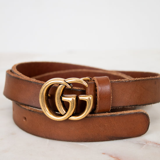Brown leather belt with gold double G buckle on a light background