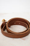 Brown leather belt with a gold buckle on a light marble background