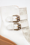 Two gold buckles on cream boot with white background