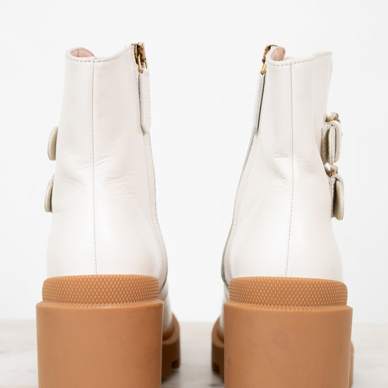 White ankle boots with brown soles on a white background