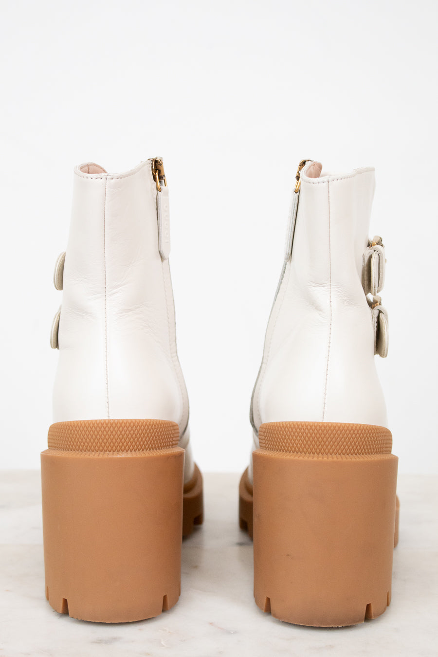 White ankle boots with brown soles on a white background