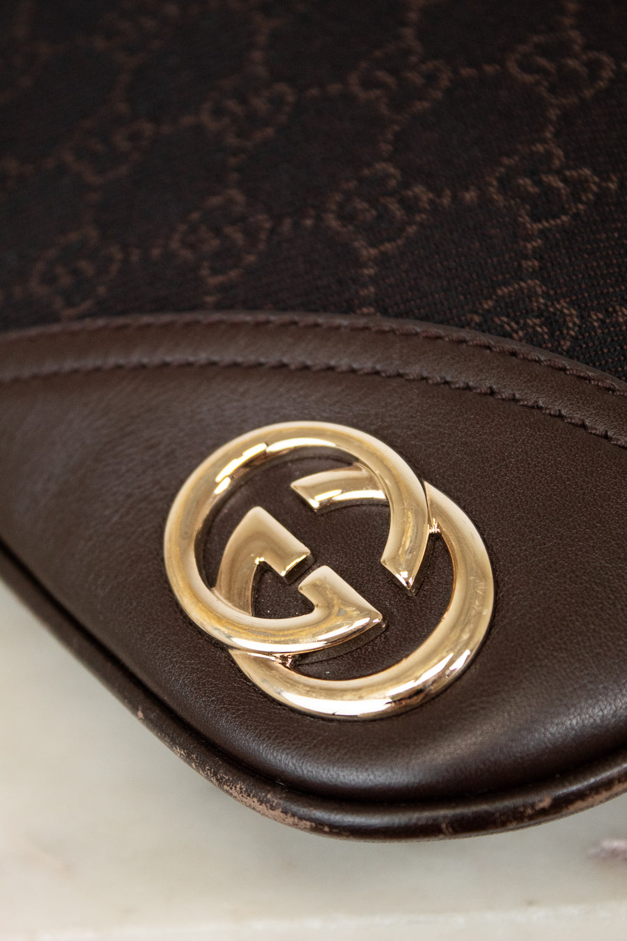 Gucci logo on brown purse with a white surface