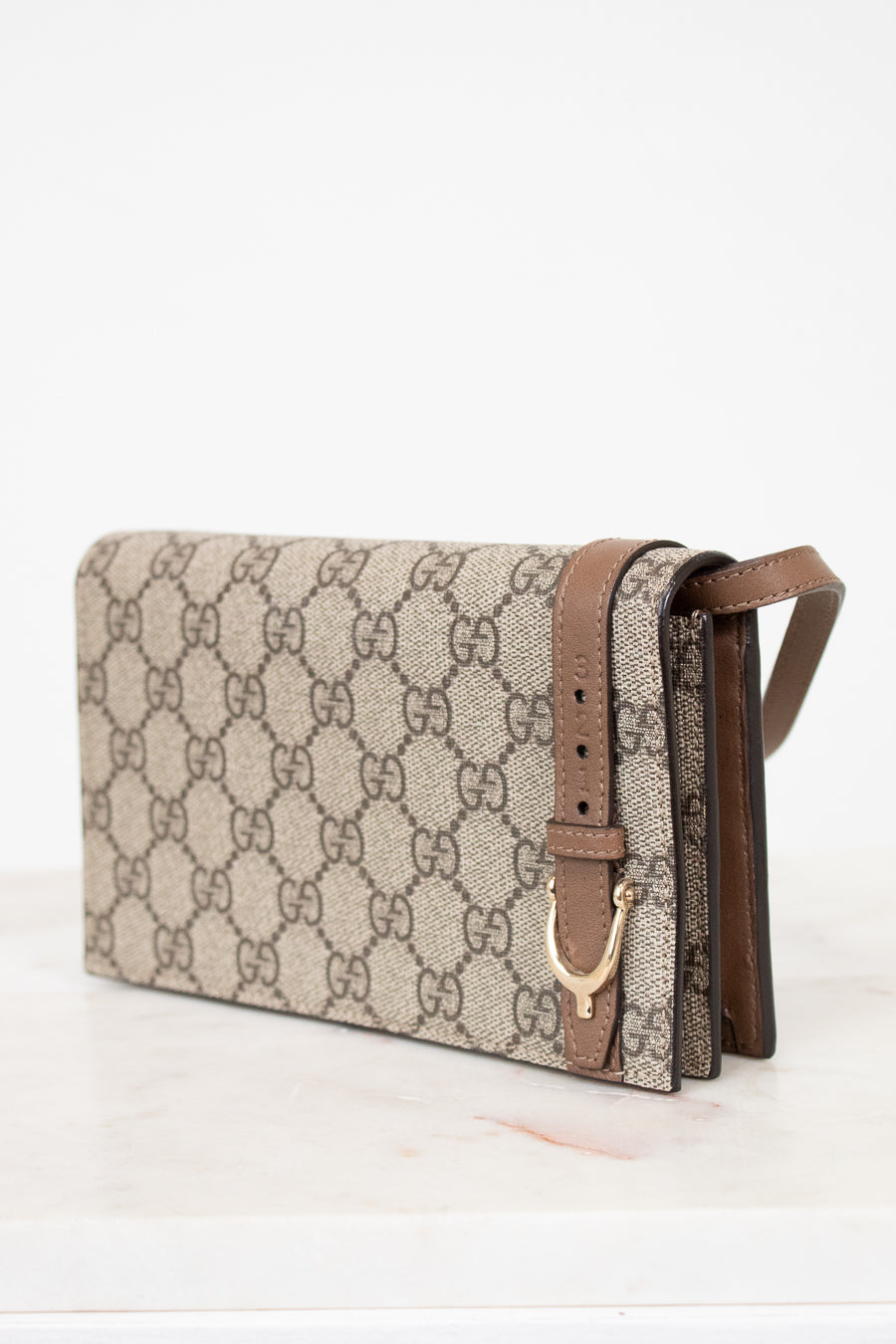 Beige handbag with brown strap on a white background