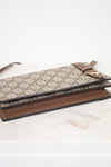 Designer handbag with patterned flap and brown base on a light background