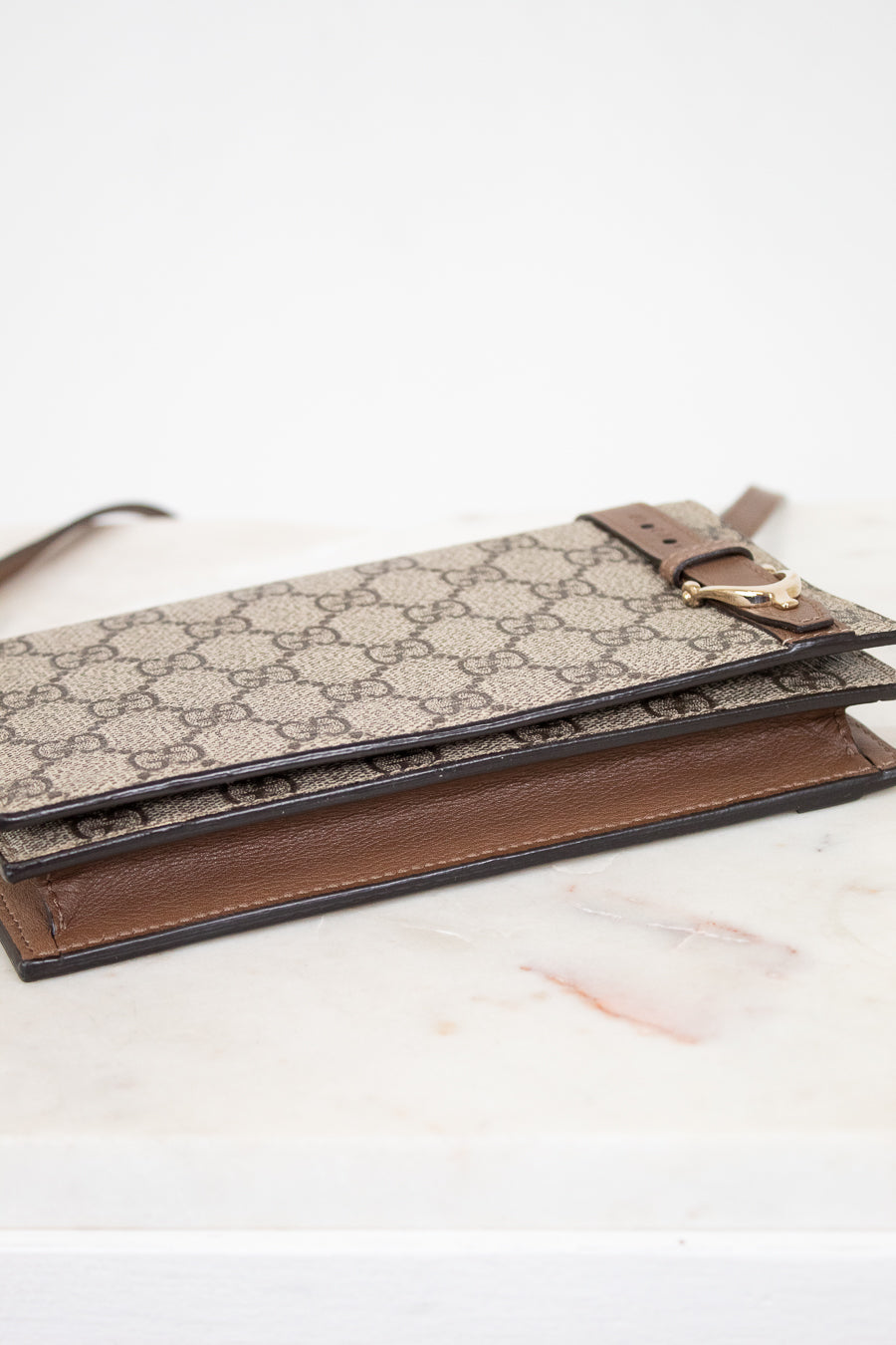 Designer handbag with patterned flap and brown base on a light background