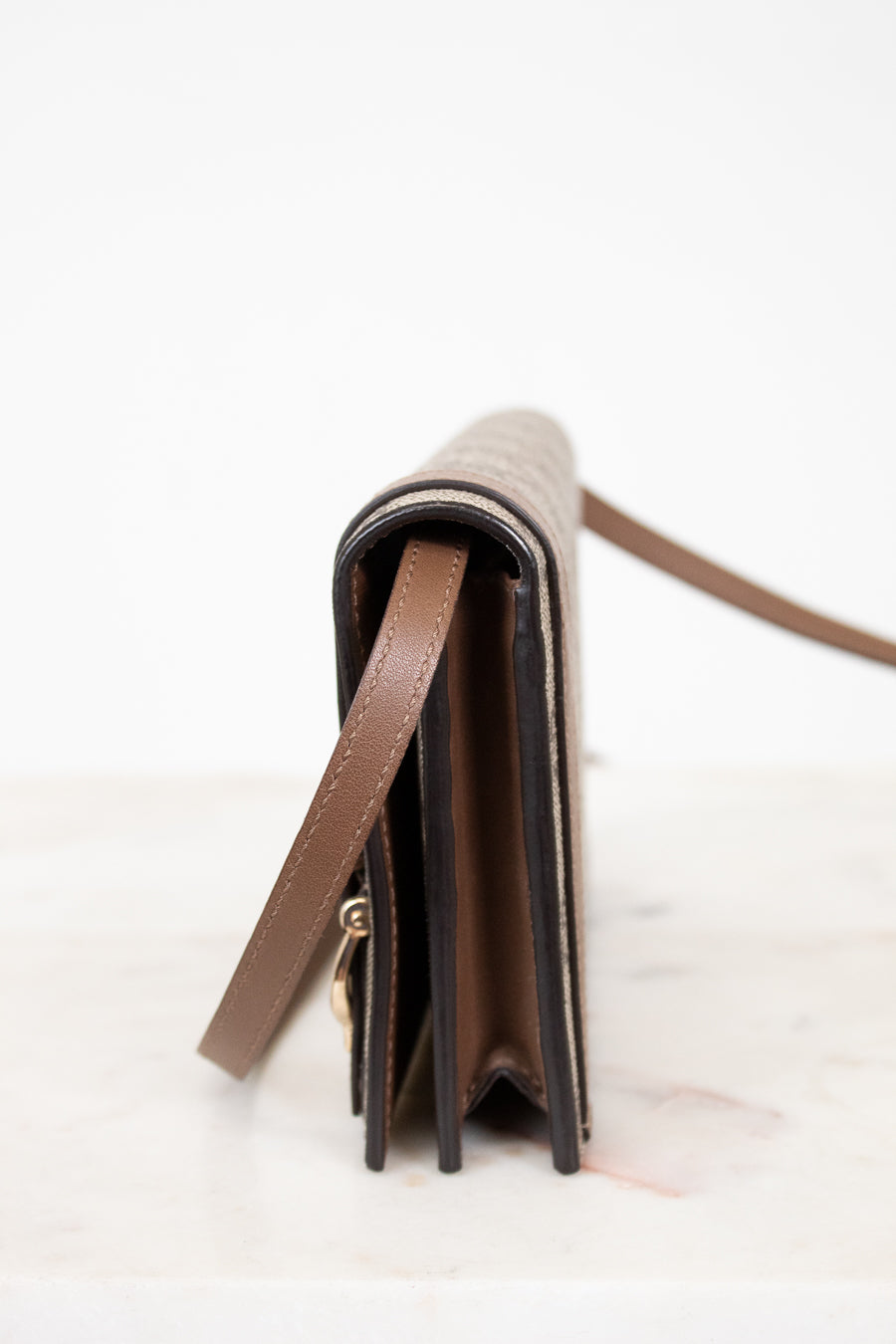 Close-up of a brown leather wallet with a strap on a white background