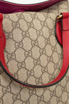Close-up of a Gucci handbag with red accents and monogram pattern.
