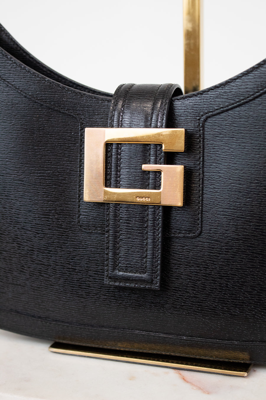 Black handbag with gold buckle on a light background