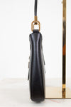 Black textured handbag with gold accents on a white background