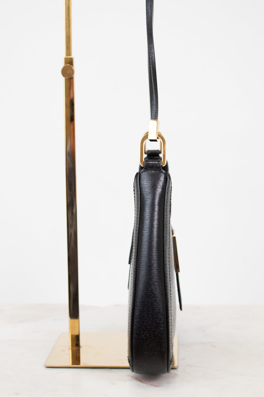 Black leather handbag with gold accents on a white background