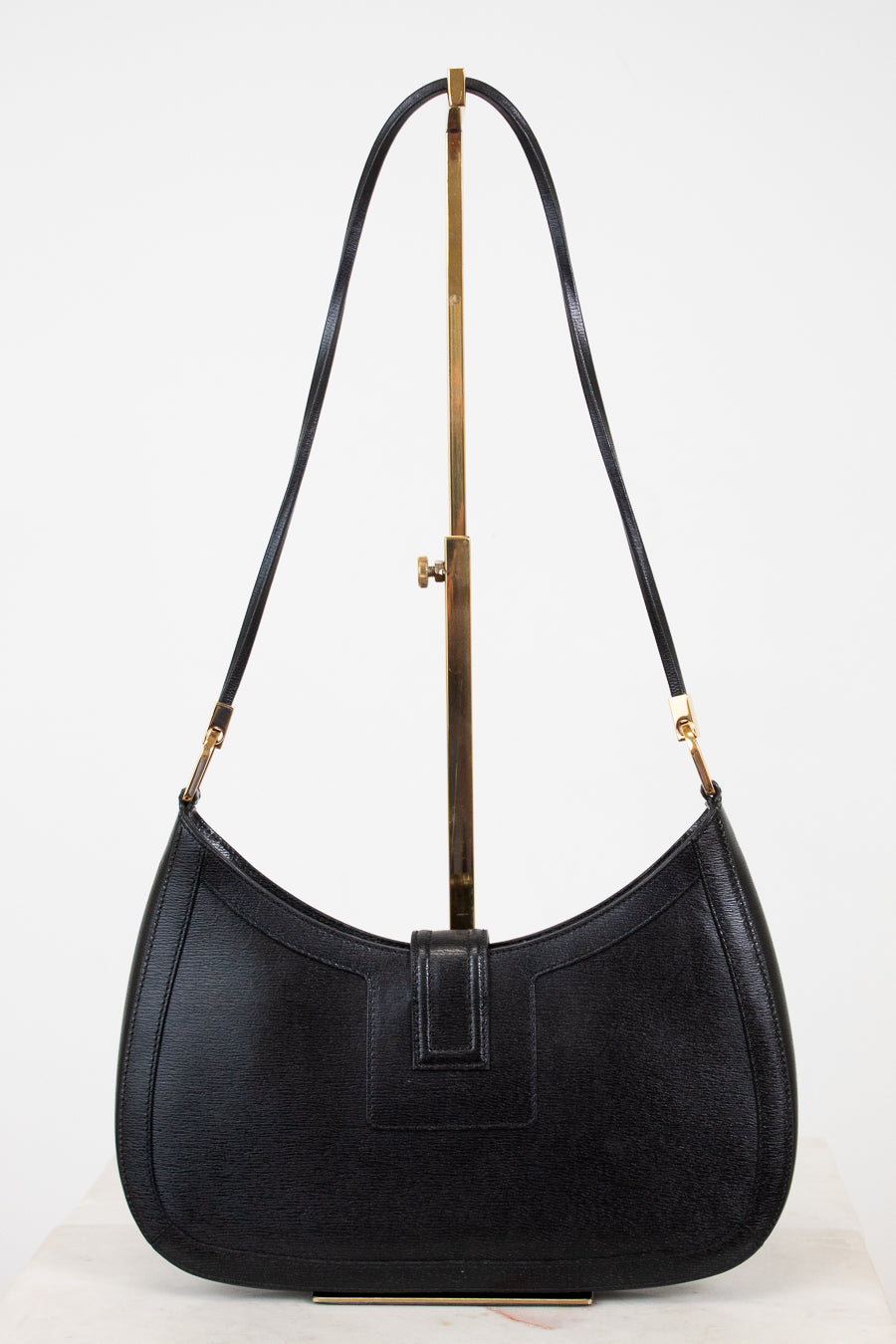 Black handbag with a gold clasp on a white background