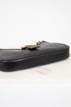 Black leather handbag with gold clasp on a light background