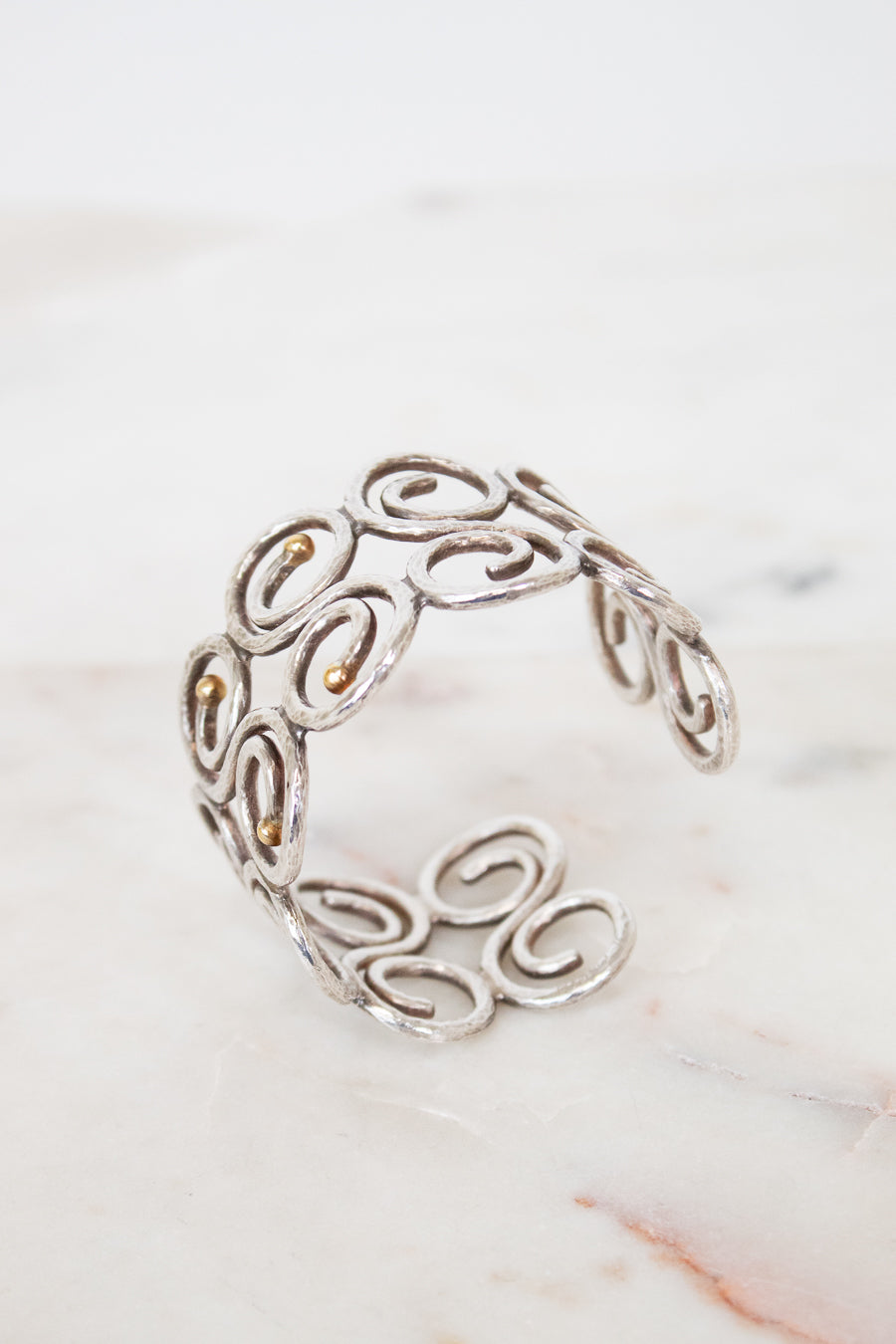 Silver bracelet with intricate designs on a marble surface
