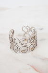 Silver cuff bracelet with intricate designs on a marble surface