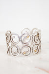 Silver cuff bracelet with gold accents on a white background