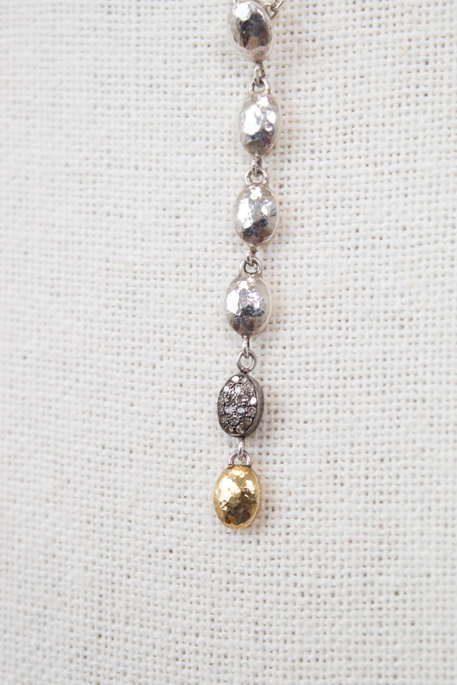 Silver and gold necklace on a textured white background