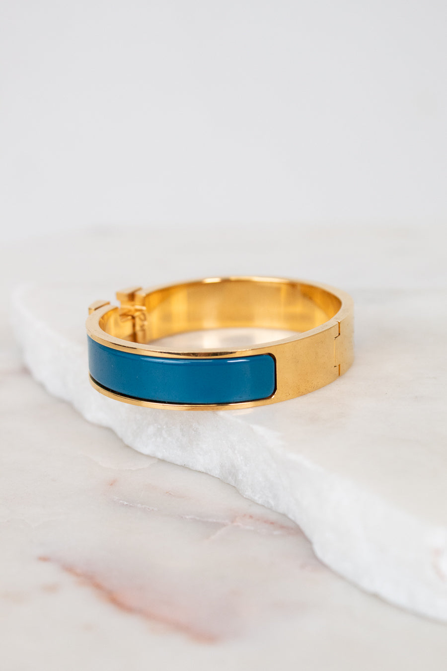 Gold bracelet with a blue band on a white marble surface