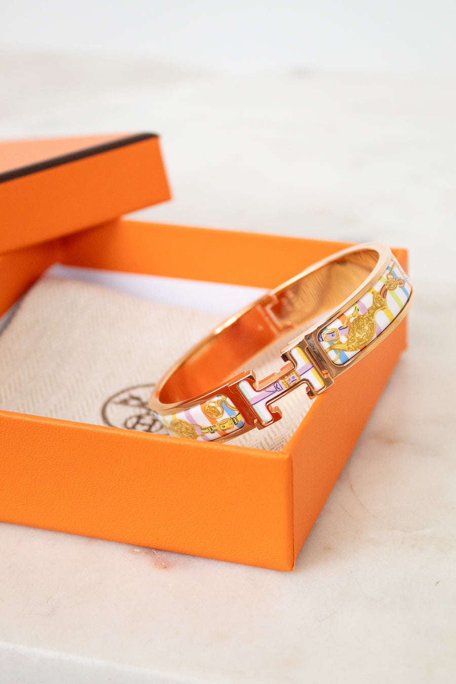 Rose gold bracelet with colorful design on an orange box