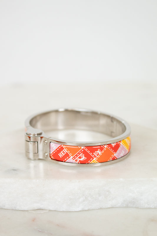 Silver bracelet with a colorful band on a white marble surface