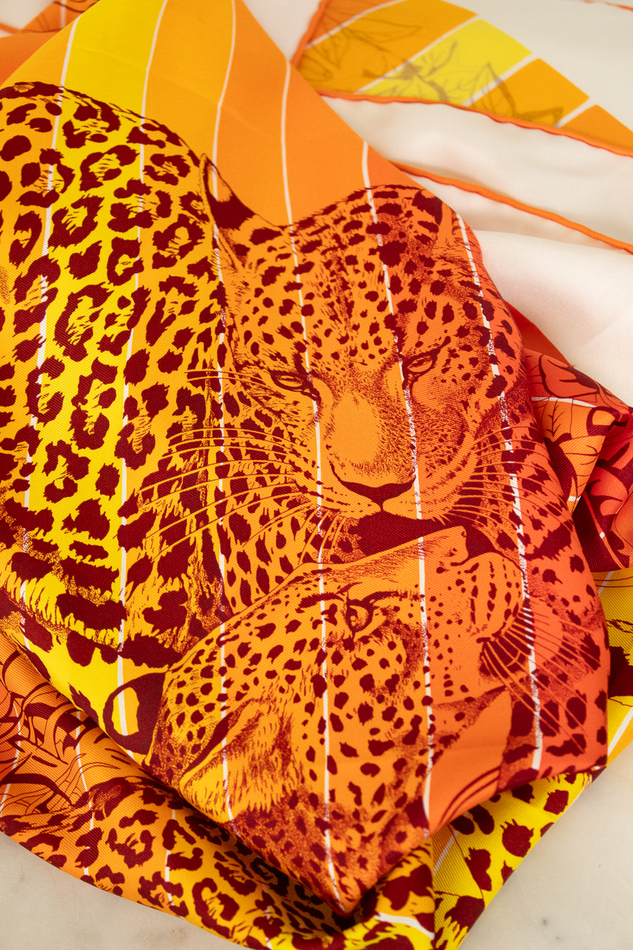 Leopard print scarf with orange and yellow colors on a white background