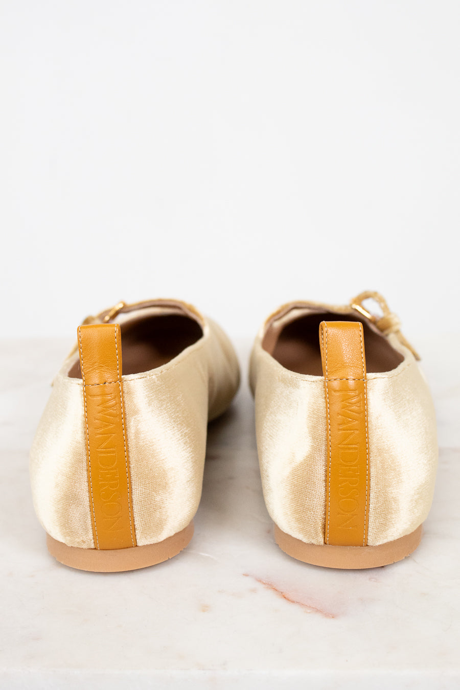 Pair of gold shoes with orange accents on a white background
