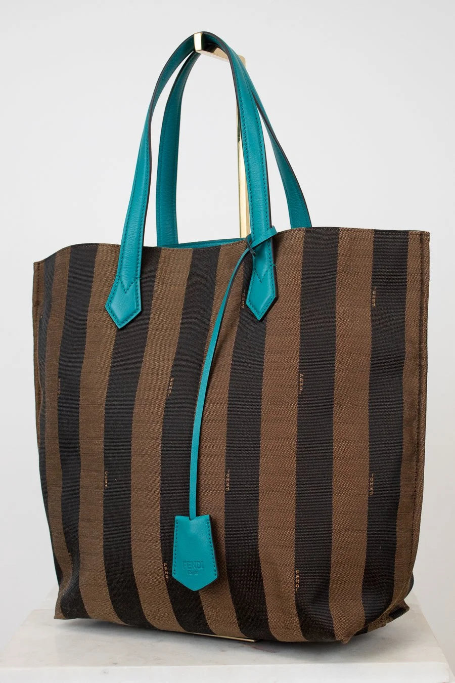 Striped tote bag with turquoise handles and accents on a white background