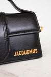 Black handbag with 'Jacquemus' branding on a marble surface