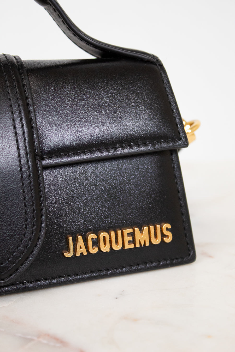 Black handbag with 'Jacquemus' branding on a marble surface