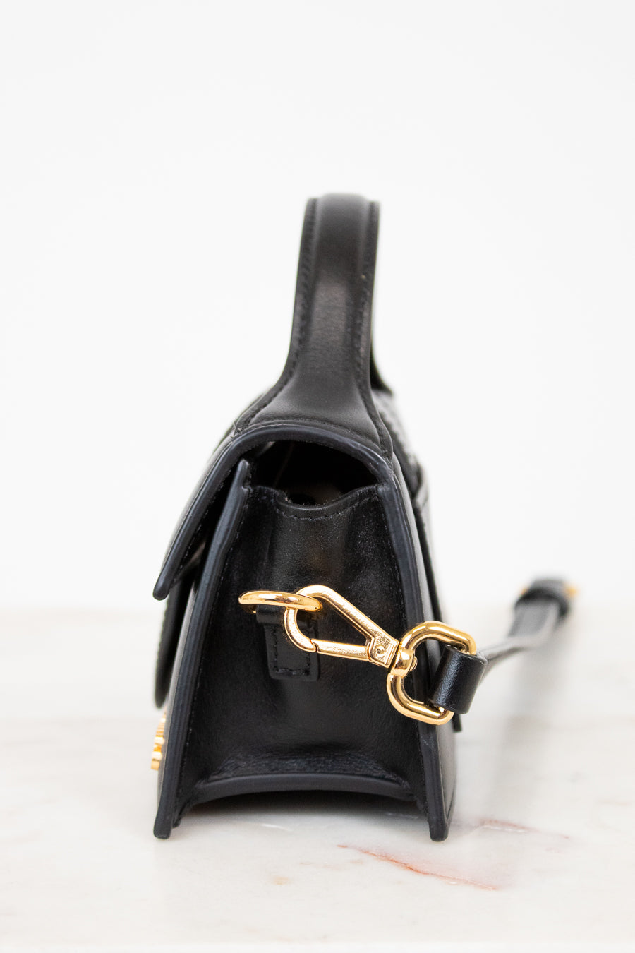 Black handbag with gold clasp on a light background