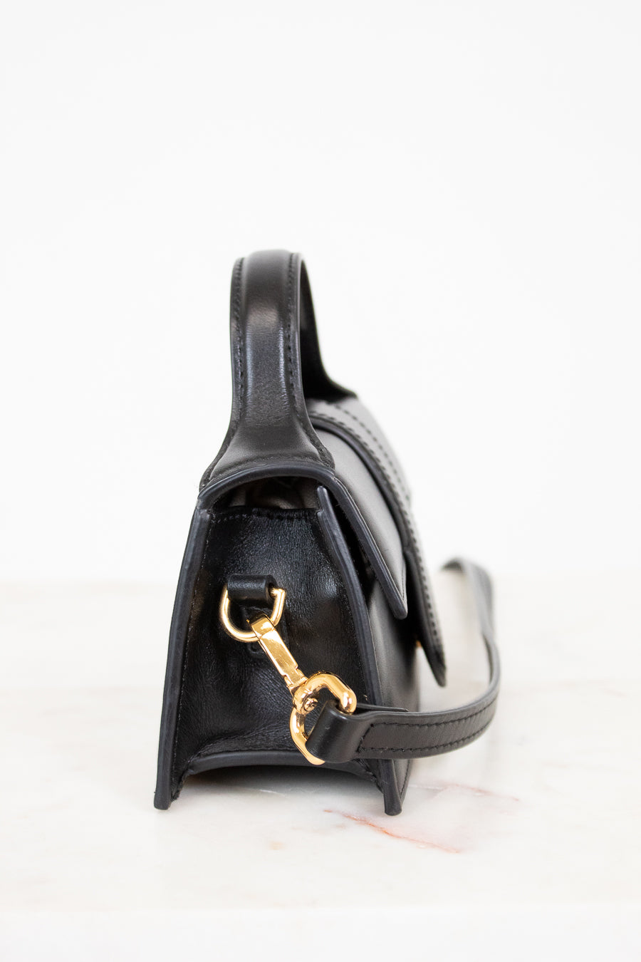 Black handbag with gold clasp on a white background