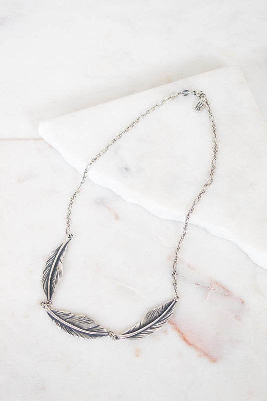 Silver feather necklace on a marble surface