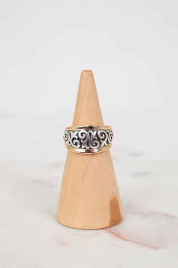 Silver ring on a wooden cone against a white background