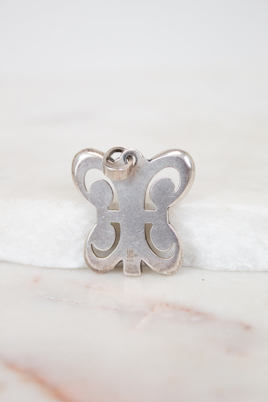 Silver butterfly-shaped pendant on a white background