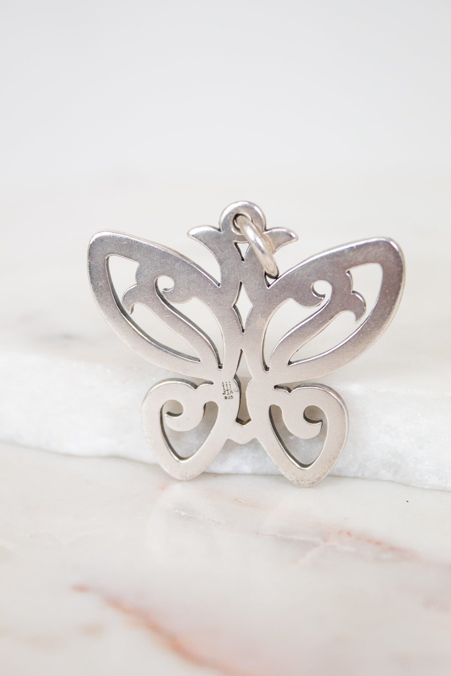 Silver butterfly pendant on a marble surface