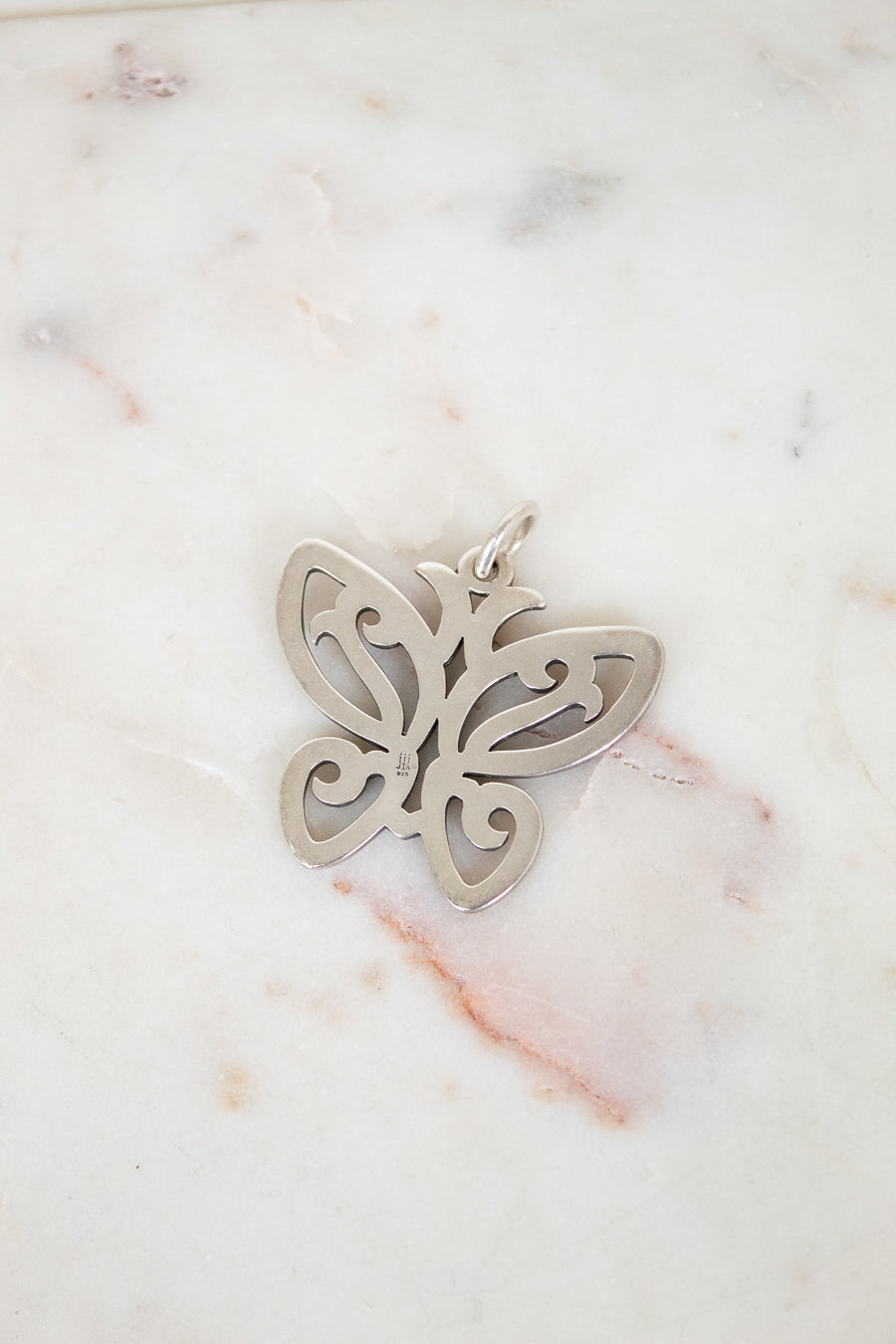 Silver butterfly pendant on a marble surface