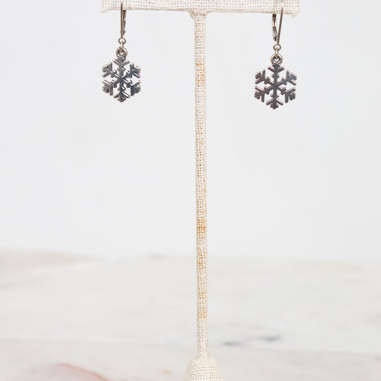 Snowflake earrings on a stand with a white background