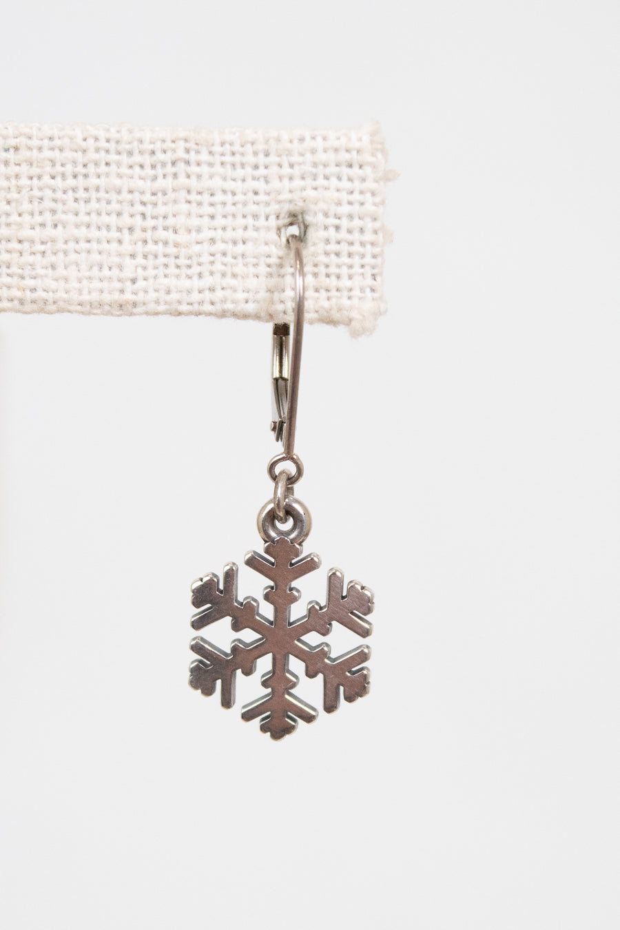 Silver snowflake charm on a white background