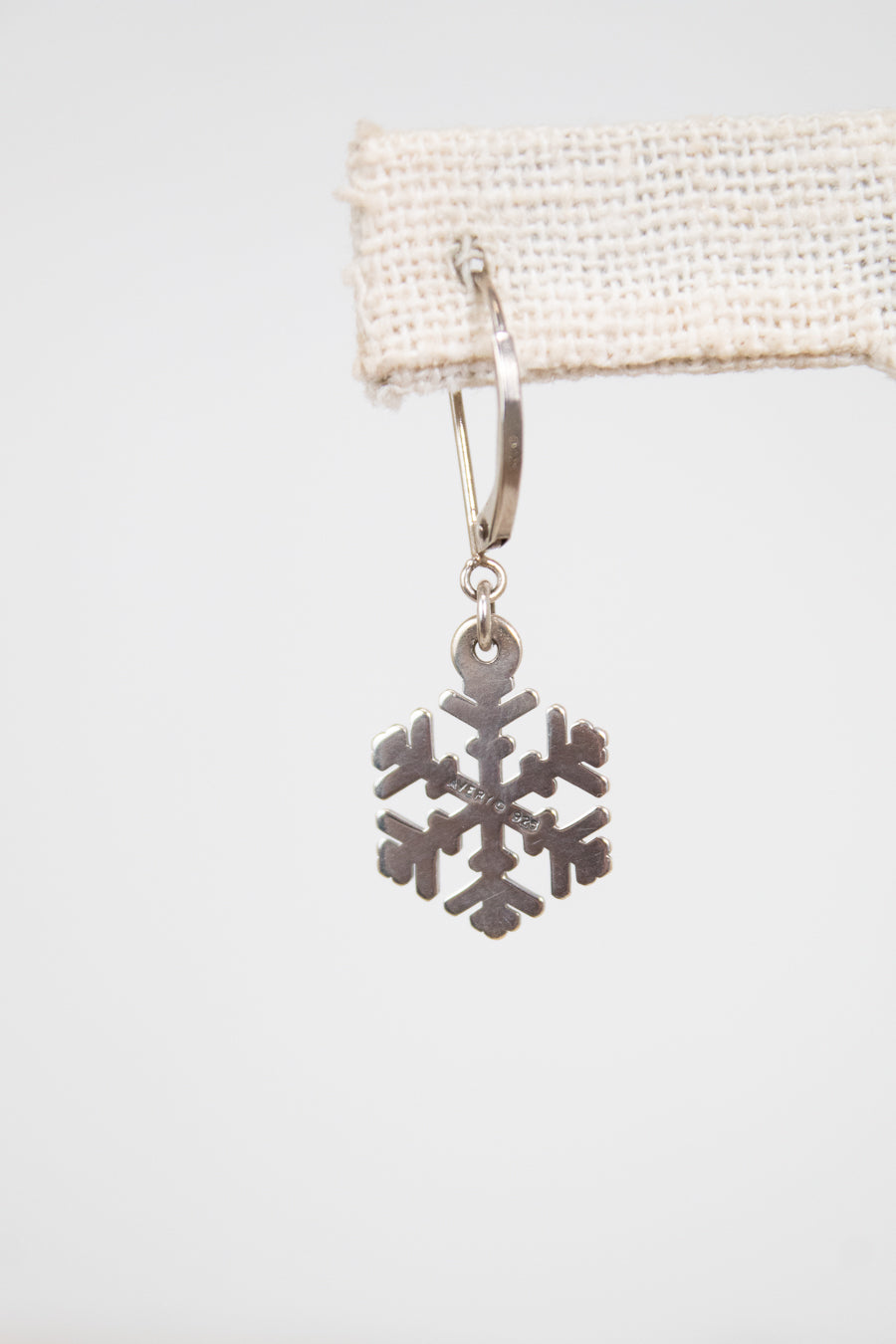 Silver snowflake earring on a white background