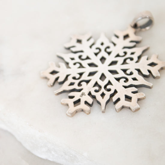 Silver snowflake pendant on a light background