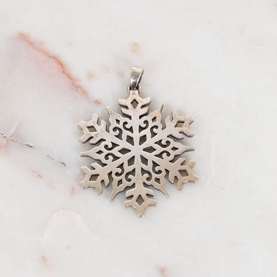 Silver snowflake pendant on a marble surface