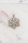 Silver snowflake pendant on a marble surface