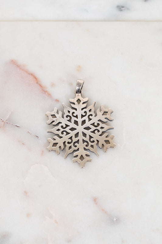 Silver snowflake pendant on a marble surface
