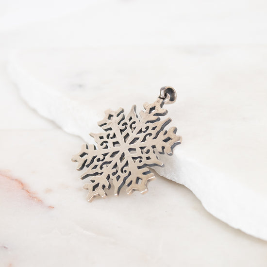 Silver snowflake-shaped pendant on a white background